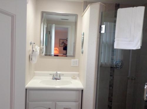a white bathroom with a sink and a shower at Island House Beach Resort 21 in Point O'Rocks