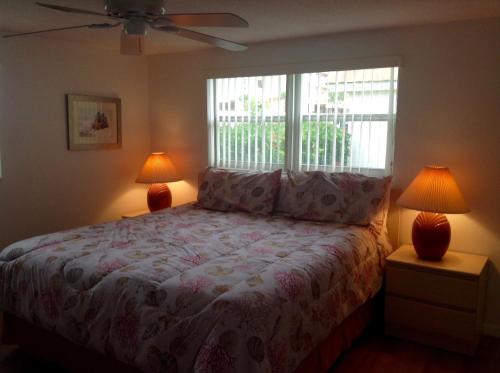 a bedroom with a bed with two lamps and a window at Island House Beach Resort 21 in Point O'Rocks
