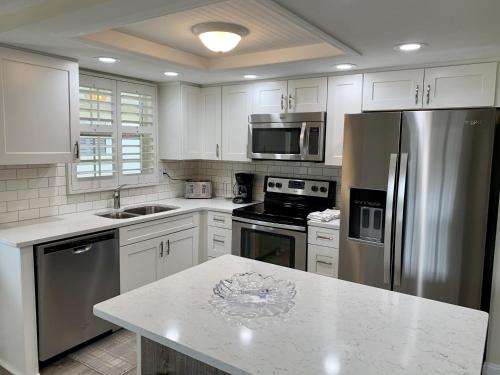 a kitchen with white cabinets and a stainless steel refrigerator at Island House Beach Resort 34 in Siesta Key