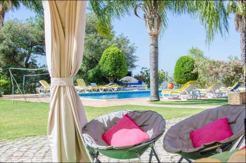 two chairs with pink pillows sitting under a canopy at Idyllic Farm House Amazing Landscap Sea View in Loulé