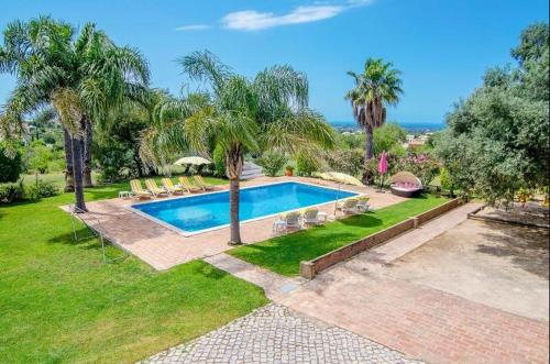 a swimming pool in a yard with palm trees at Idyllic Farm House Amazing Landscap Sea View in Loulé