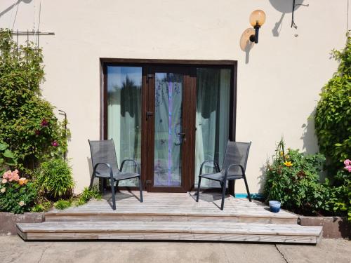 two chairs sitting on a wooden porch in front of a door at Mustvee Creek Cottage in Mustvee