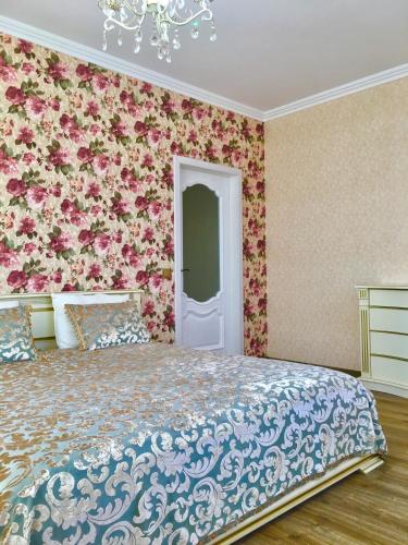 a bedroom with a bed with a floral wall at Люкс в Жмеринке in Zhmerynka