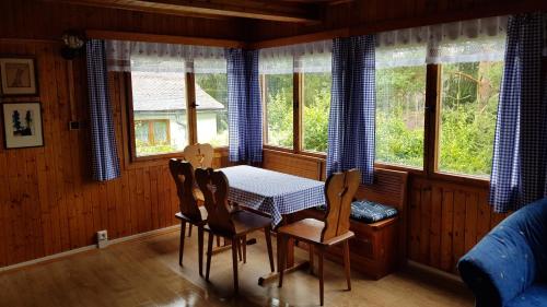 une salle à manger avec une table, des chaises et des fenêtres dans l'établissement Chaloupka v pohodě, à Jetřichovice
