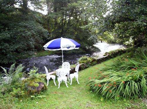 a table and chairs under an umbrella next to a river at Rydal Lodge in Rydal