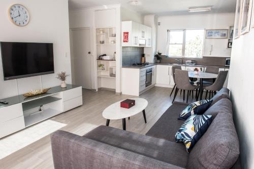 sala de estar con sofá, mesa y cocina en Lotus Stay Manly - Apartment 29G en Sídney
