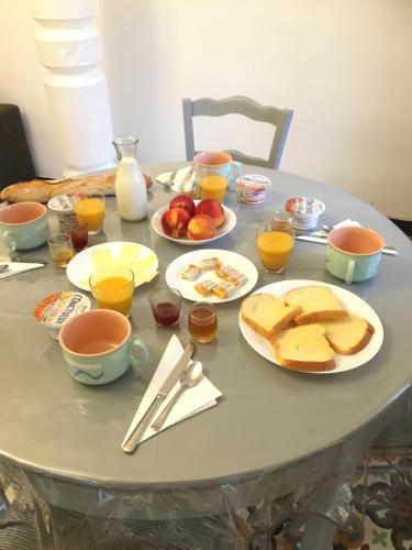 a table with plates of bread and orange juice at Chez Tatie Ménie in Fraissé-des-Corbières