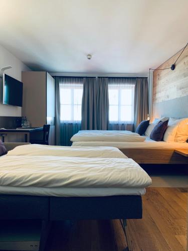 two beds in a hotel room with windows at Stadthotel Kachelofen in Krumbach