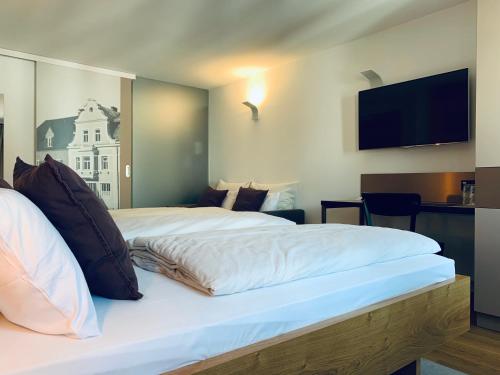 a hotel room with two beds and a flat screen tv at Stadthotel Kachelofen in Krumbach