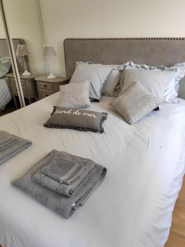 un lit blanc avec des serviettes et des oreillers dessus dans l'établissement Gîte de la roseraie, à Quiberville