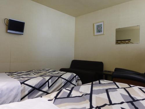 a room with two beds and a chair and a tv at Oimatsuen in Saku