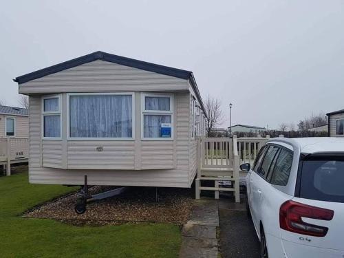 a tiny house is parked next to a car at Cosy caravans Sandhills 175 butlins Skegness resort in Ingoldmells