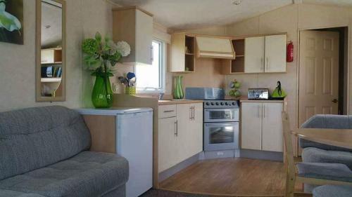 a small kitchen with a couch and a chair in it at Cosy caravans Sandhills 175 butlins Skegness resort in Ingoldmells