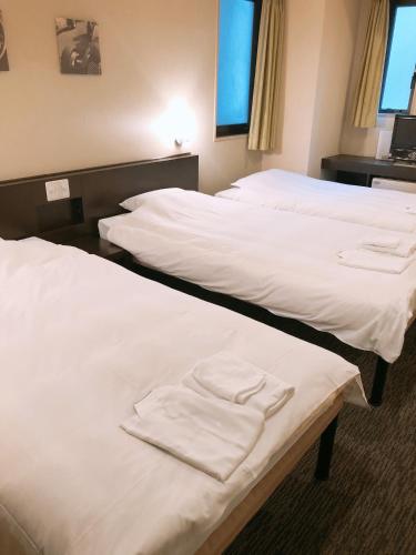 two beds in a hotel room with white sheets at Business Hotel Sunpu in Shizuoka