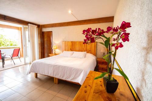 a bedroom with a bed and a vase with flowers on a table at La Pirámide del Tepozteco in Tepoztlán