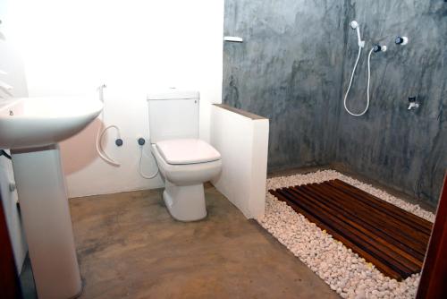 a bathroom with a toilet and a sink and a shower at Prime Surfers Bungalow in Arugam Bay