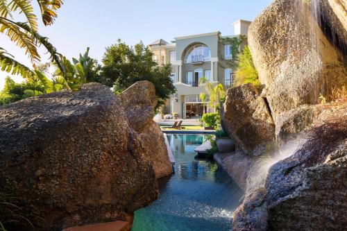 a swimming pool with rocks in front of a house at 21 Nettleton Boutique Hotel & Luxury Residence in Cape Town