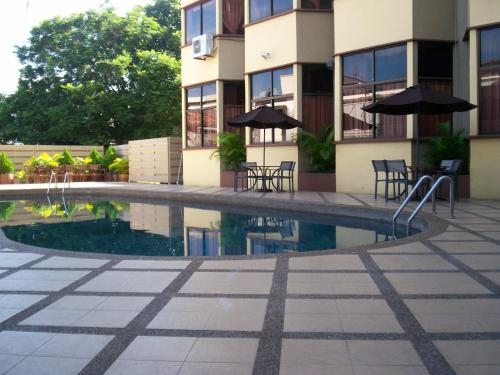 a swimming pool with chairs and umbrellas in front of a building at Hotel Grand Crystal in Alor Setar