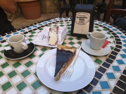 a slice of pie on a plate on a table with two cups at Residence San Martino in Erice
