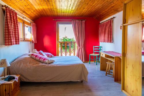 een slaapkamer met rode muren, een bed en een bureau bij Chez René in Ammerschwihr