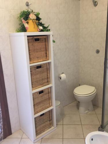 a bathroom with a toilet and a shelf with baskets at La casa sotto la torre in Chia
