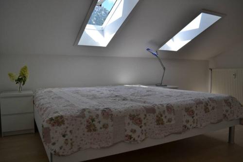 a bedroom with a bed with a floral bedspread and two windows at Ferienwohnung Stimmer in Grainau