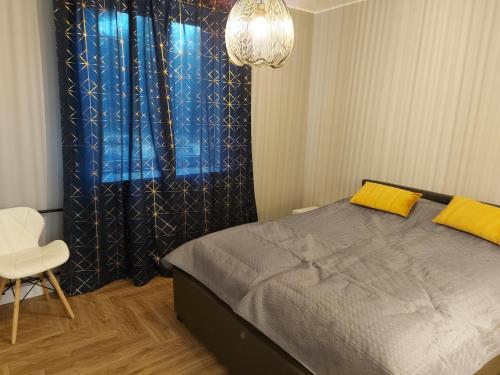 a bedroom with a bed and a chair and a chandelier at GS Apartament Olsztyn in Olsztyn
