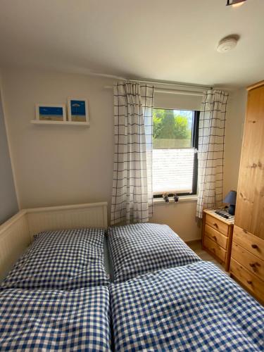 ein Schlafzimmer mit einem Bett mit einer karierten Bettdecke und einem Fenster in der Unterkunft Ostseebungalow HaningHuus in Diedrichshagen