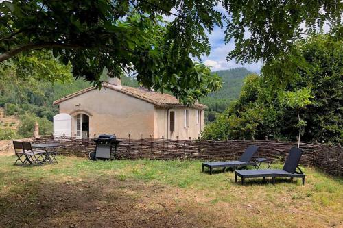 a house with two chairs and a grill in a yard at Le Gîte - La Ferme du Pouget in Saint-Jean-du-Gard