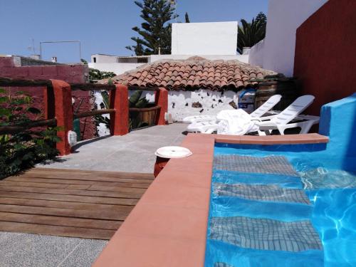 a pool with white chairs next to a house at I MITI ViviendaVacacional in Chio