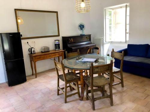 a living room with a table and a piano at Le Gîte - La Ferme du Pouget in Saint-Jean-du-Gard