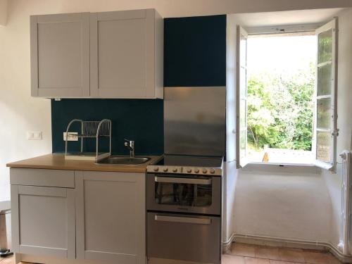 a kitchen with white cabinets and a sink and a window at Le Gîte - La Ferme du Pouget in Saint-Jean-du-Gard