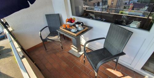 einen Balkon mit 2 Stühlen und einem Tisch mit Obst darauf in der Unterkunft Appartement Schönblick STADTTEIL BAD MÜNSTER AM STEIN EBERNBURG in Bad Kreuznach