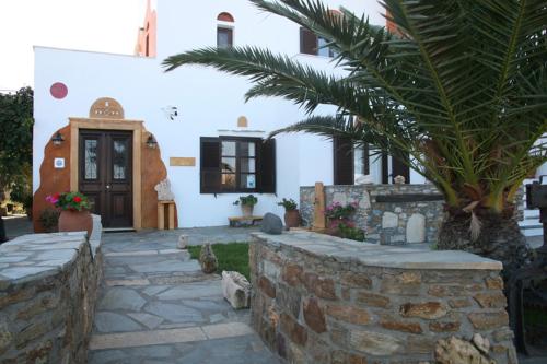 a house with a palm tree and a stone wall at Villa Danai in Agia Anna Naxos