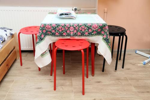 una mesa con dos taburetes rojos con un paño. en Tanie Noclegi Mieszkanka, en Żyrardów