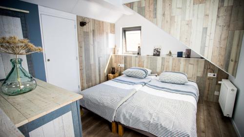 a bedroom with a bed and a wooden wall at B&B Joeys place in Egmond aan Zee