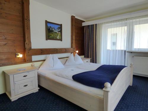 um quarto com uma cama grande e um cobertor azul em Panoramahotel em Sankt Johann in Tirol
