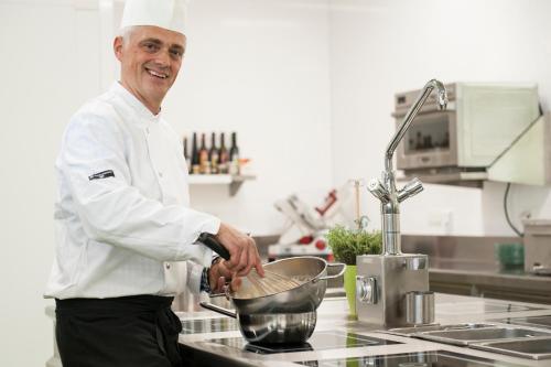 a chef is stirring a pot in a kitchen at Hotel Staribacher Südsteiermark in Leibnitz