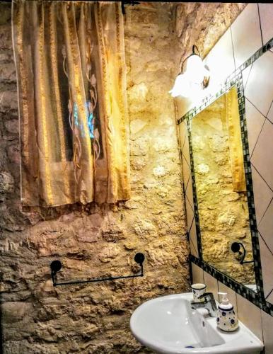 a stone bathroom with a sink and a mirror at Torre Rodosta in Modica