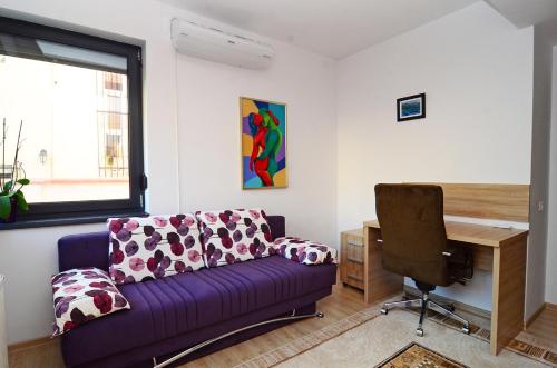 a living room with a purple couch and a desk at Luxury apartment by the park / Arch of Triumph in Bucharest