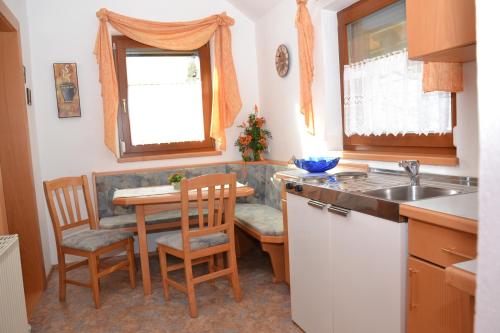 eine Küche mit einem Tisch, Stühlen und einem Waschbecken in der Unterkunft Gästehaus Bachmann in Hermagor