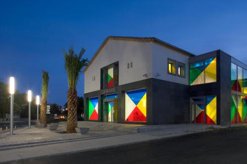 a building with a colorful facade with a palm tree at Appartement cosy Sérignan in Sérignan