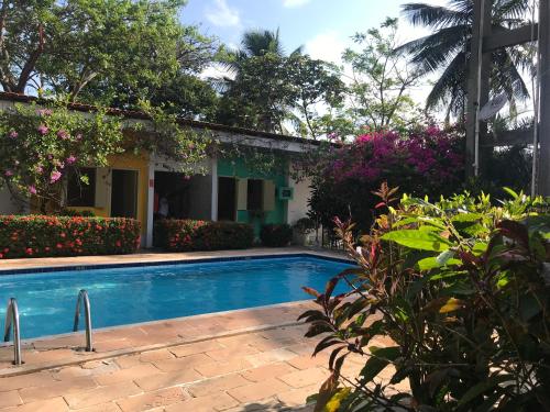 a swimming pool in front of a house with flowers at Pousada Santa Bárbara in Maruda