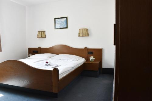 a bedroom with a large bed with white sheets at Hotel Goldene Rose in Ebersbach an der Fils