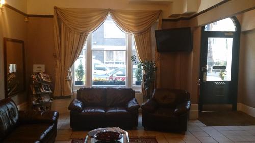 uma sala de estar com duas cadeiras de couro e uma televisão em Hyde Park Court Hotel em Londres