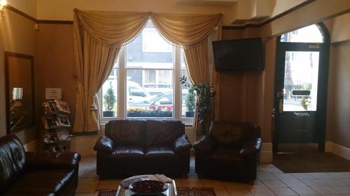 a living room with two leather chairs and a television at Hyde Park Court Hotel in London