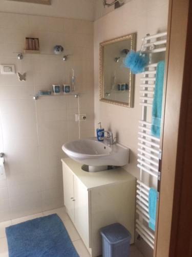 ein weißes Badezimmer mit einem Waschbecken und einem Spiegel in der Unterkunft La Casa del Glicine in Tarzo