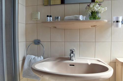 a bathroom with a sink and a vase of flowers at Hotel Goldene Rose in Ebersbach an der Fils