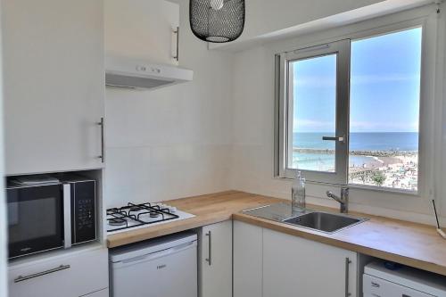 uma cozinha com um lavatório, um micro-ondas e uma janela em Lala Springs Anglet - Vue océan - WIFI - Balcon em Anglet