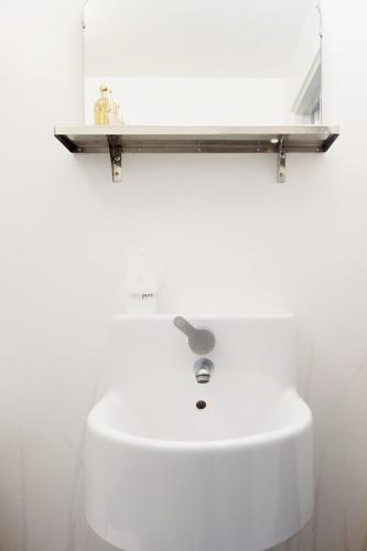 a white sink with a wooden shelf above it at Vikens bed and Breakfast in Viken